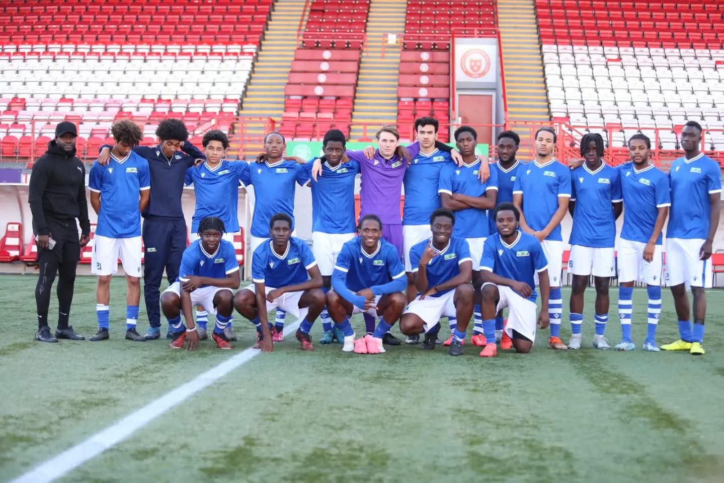 Squad of WNC athletes lined up on the pitch at the stadium